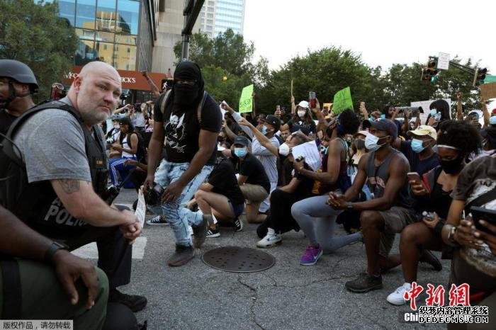 资料图：当地时间6月1日，美国乔治亚州亚特兰大市中心，警察和参加游行示威活动的民众一起跪地抗议针对美国非裔男子暴力执法的行为。